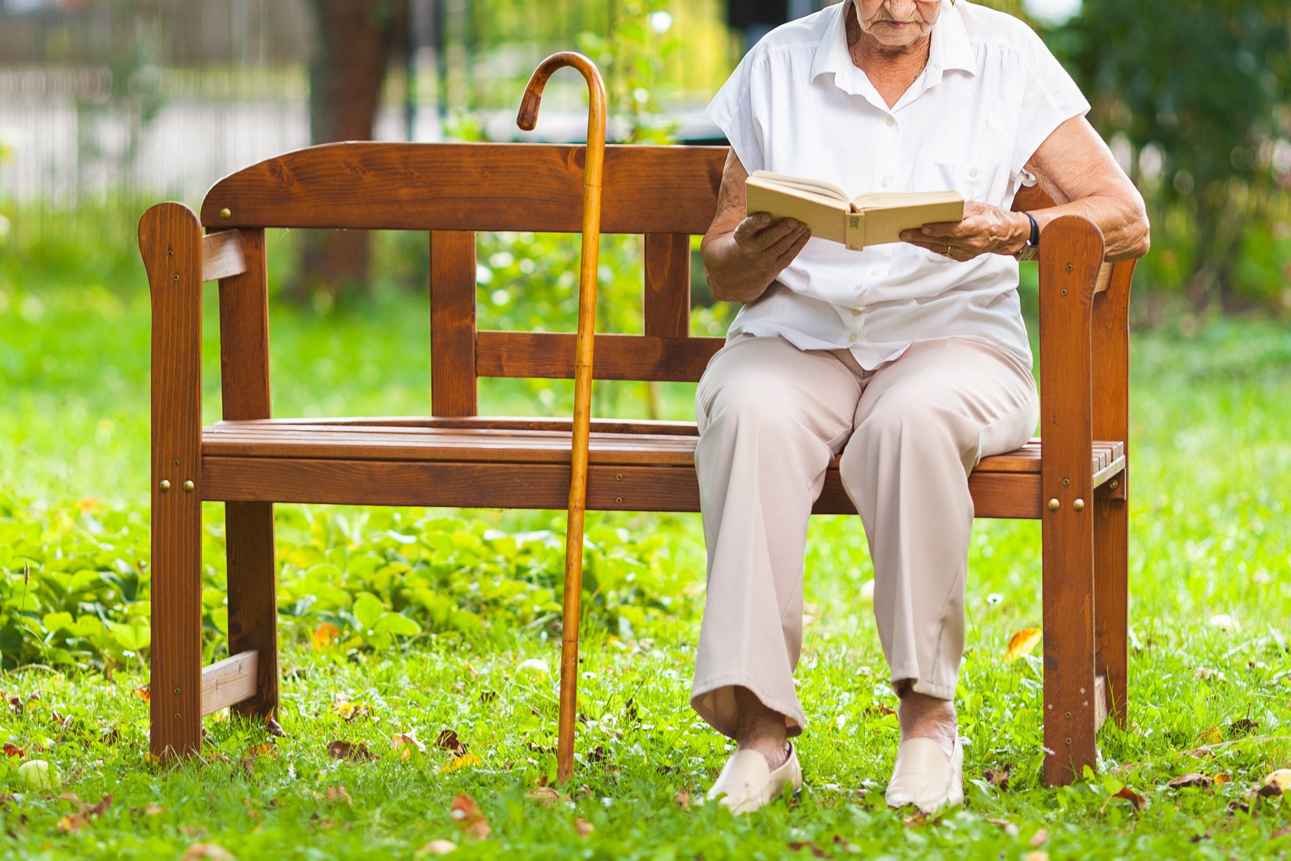 .אישה יושבת על ספסל בגינה וקוראת ספר