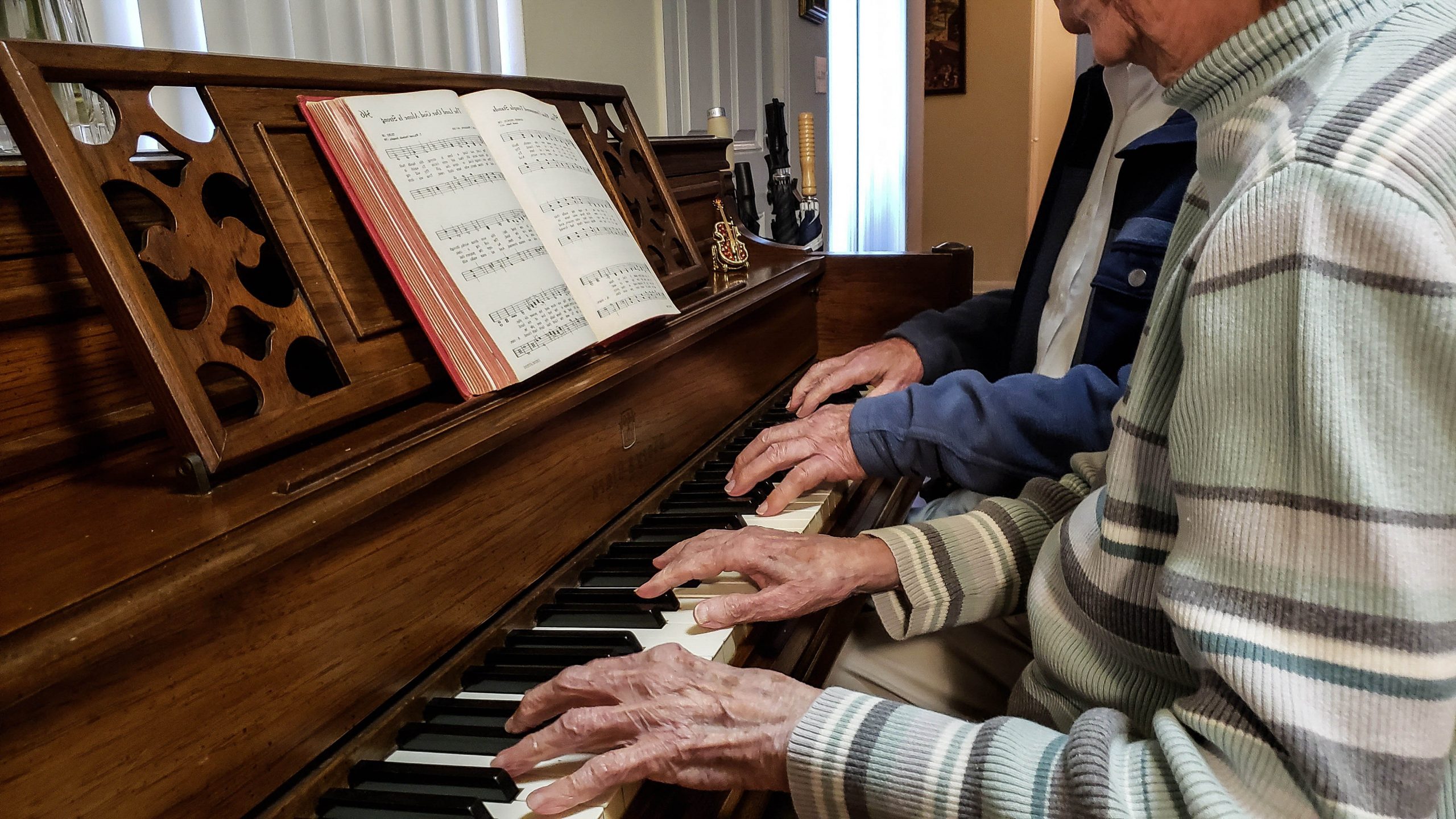 .שני גברים מבוגרים יושבים ומנגנים ביחד בפסנתר