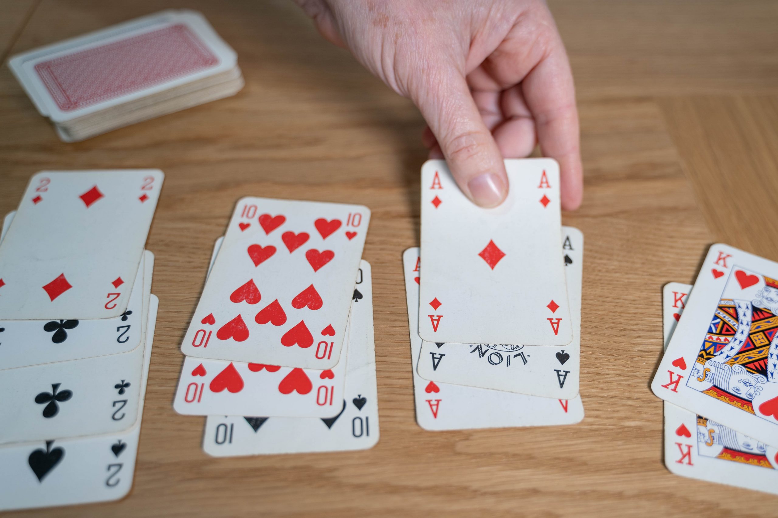 .קלפי משחק מסודרים בארבע קבוצות על שולחן. בכל קבוצה, קלפים עם אותו מספר אך צורה אחרת. יד מוסיפה קלף מתאים לאחת הקבוצות