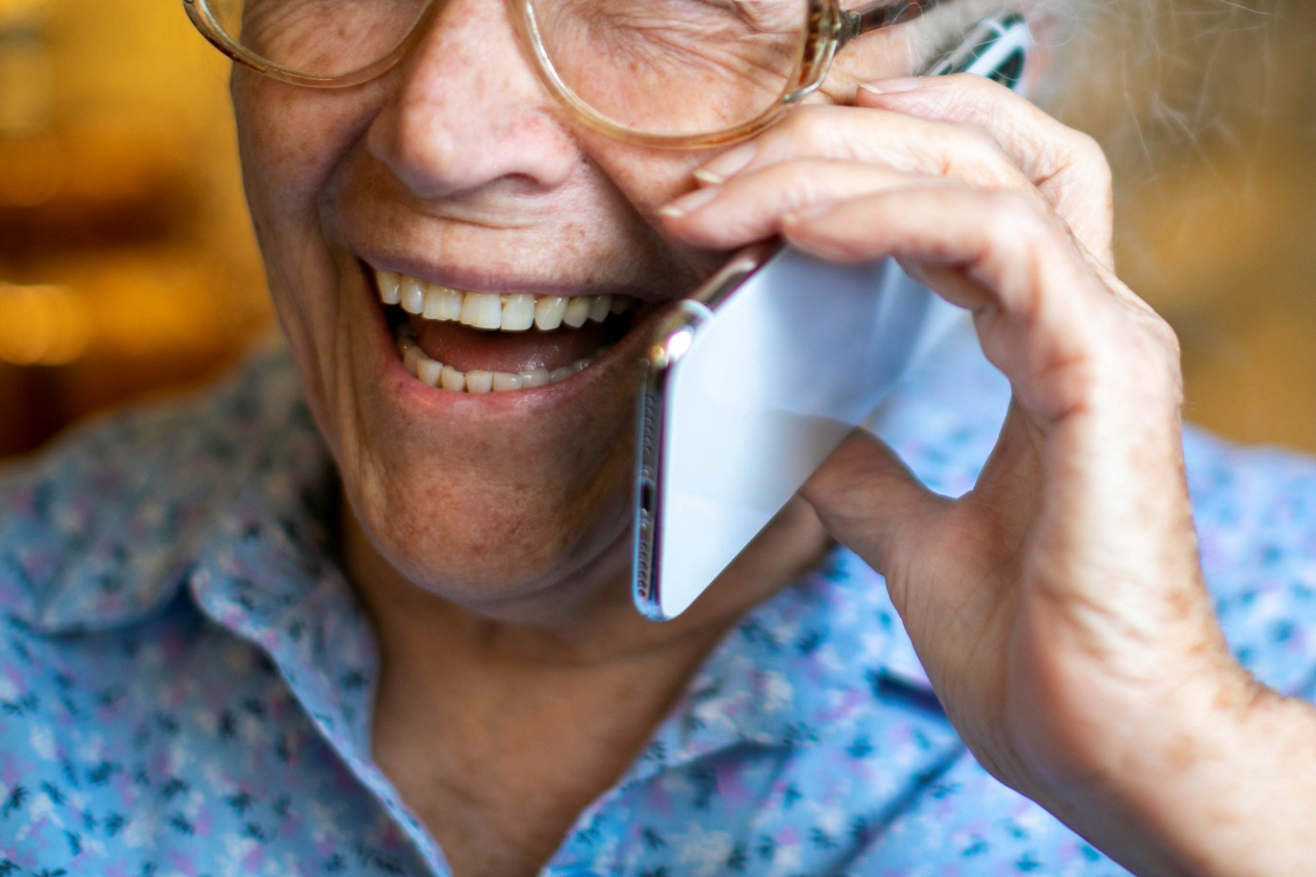 .אישה מבוגרת משוחחת בטלפון נייד ומחייכת