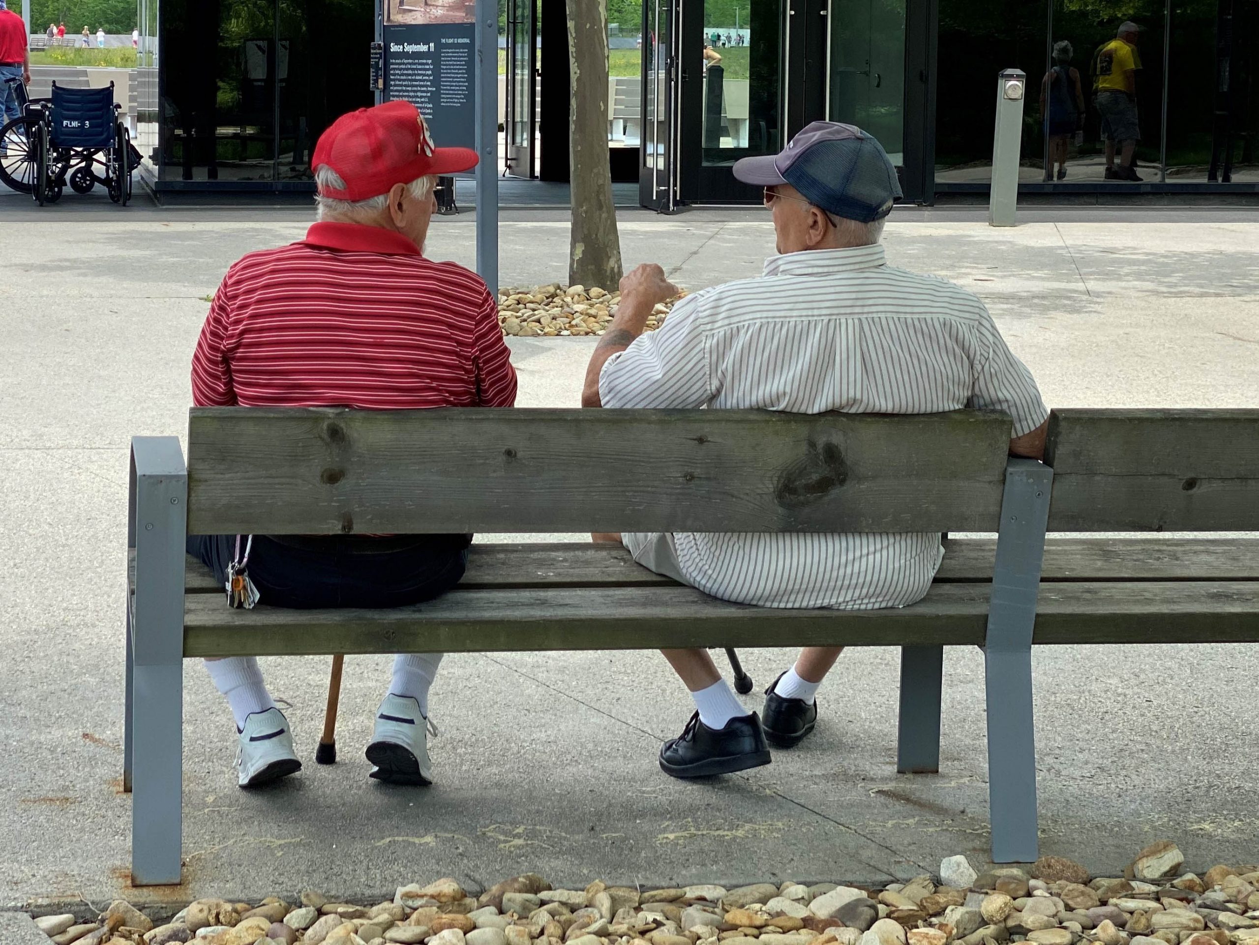 .שני אנשים מבוגרים יושבים על ספסל בחוץ ומשוחחים ביניהם