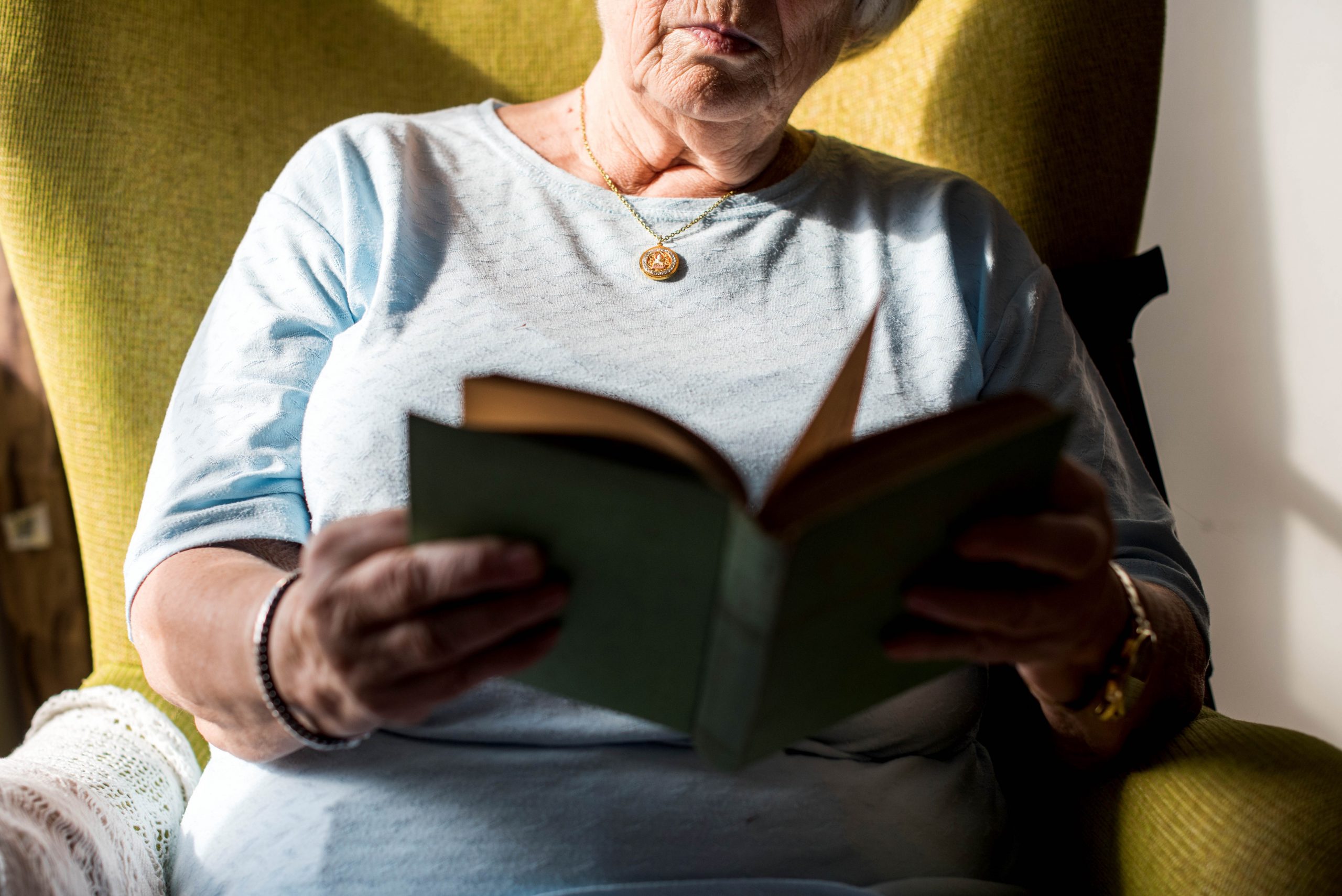 .אישה מבוגרת יושבת על ספה וקוראת ספר