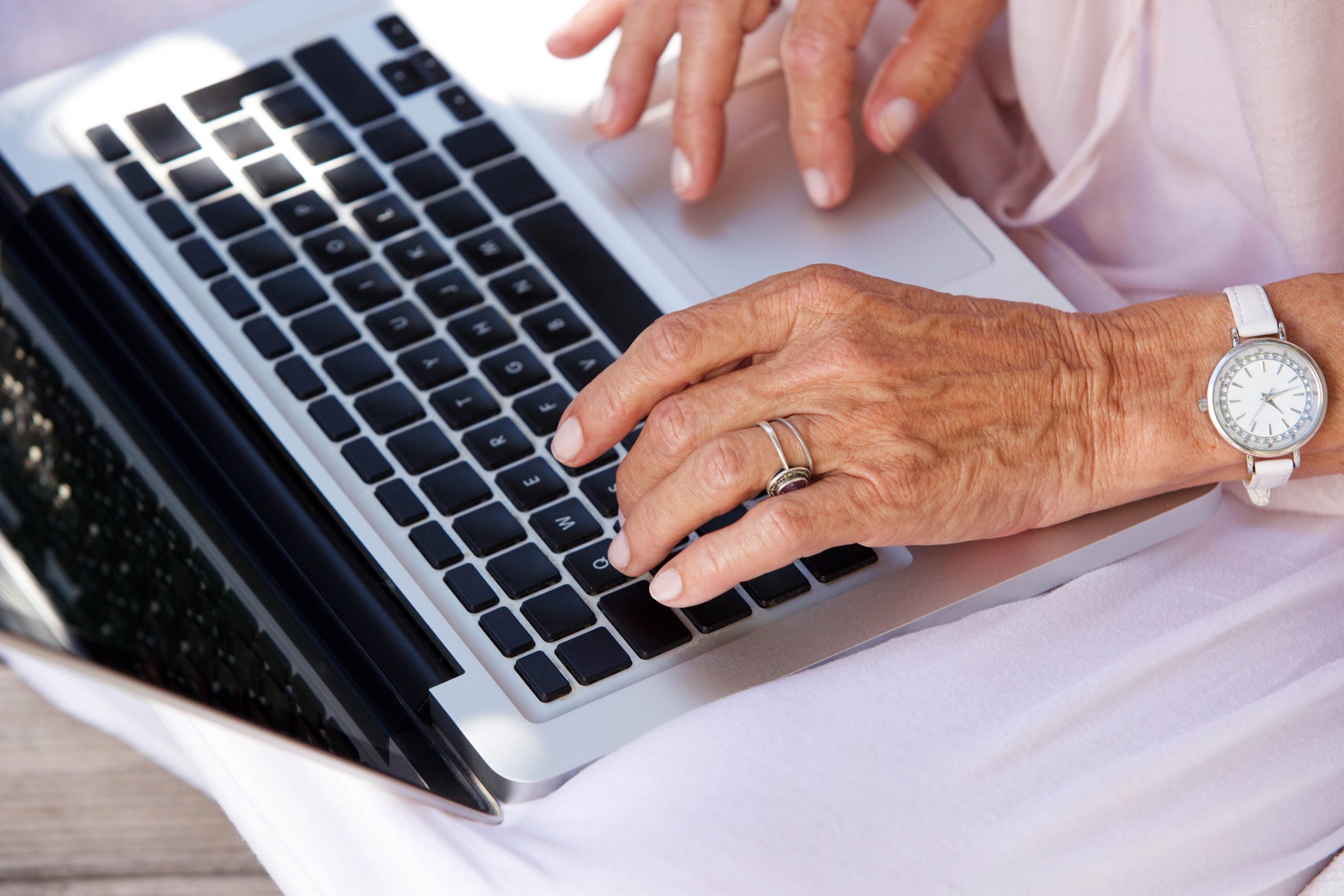 .אישה מבוגרת מקלידה על גבי מחשב נייד