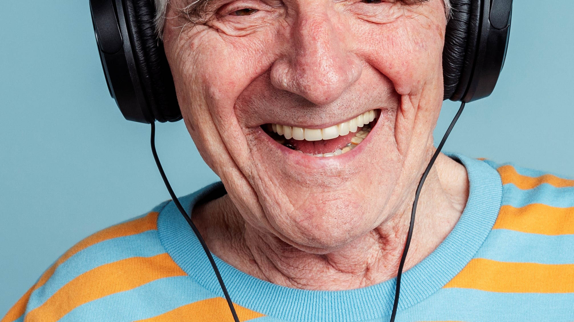 .איש זקן מחייך עם אוזניות על אוזניו