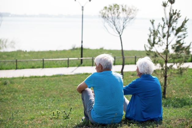 .זוג מבוגרים יושבים אחד לצד השני על דשא ומביטים אל האופק
