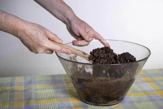 .יד מערבבת עיסה של רכיבים להכנת כדורי שוקולד, אשר נמצאים בקערה